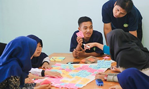 Students collaborating using post-its with a teacher who is engaging in a conversation with them.